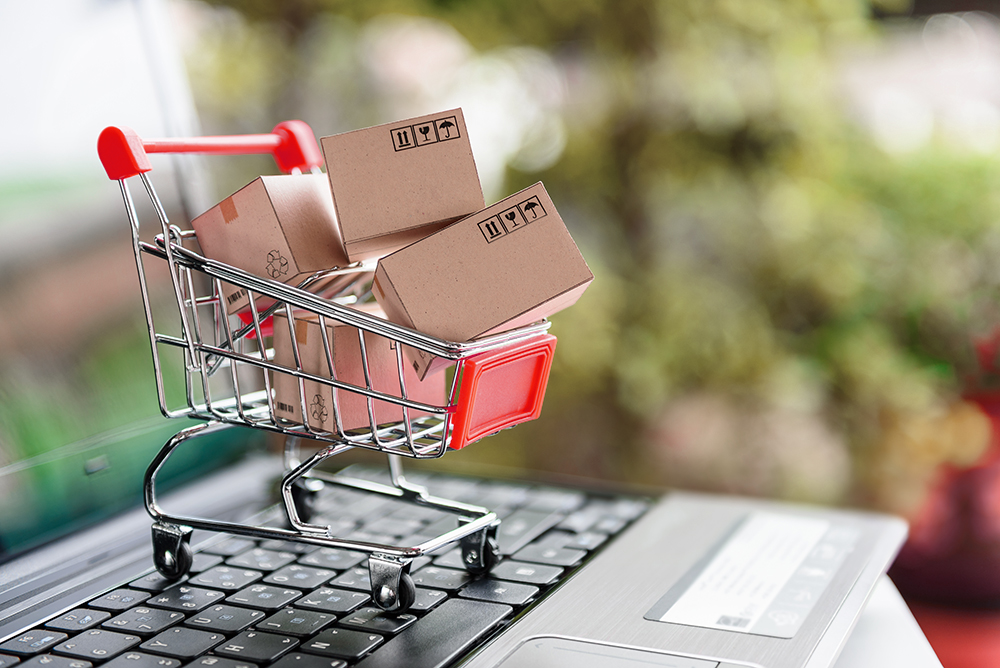 Small shopping trolley full of boxes on a laptop -Online retail the new normal